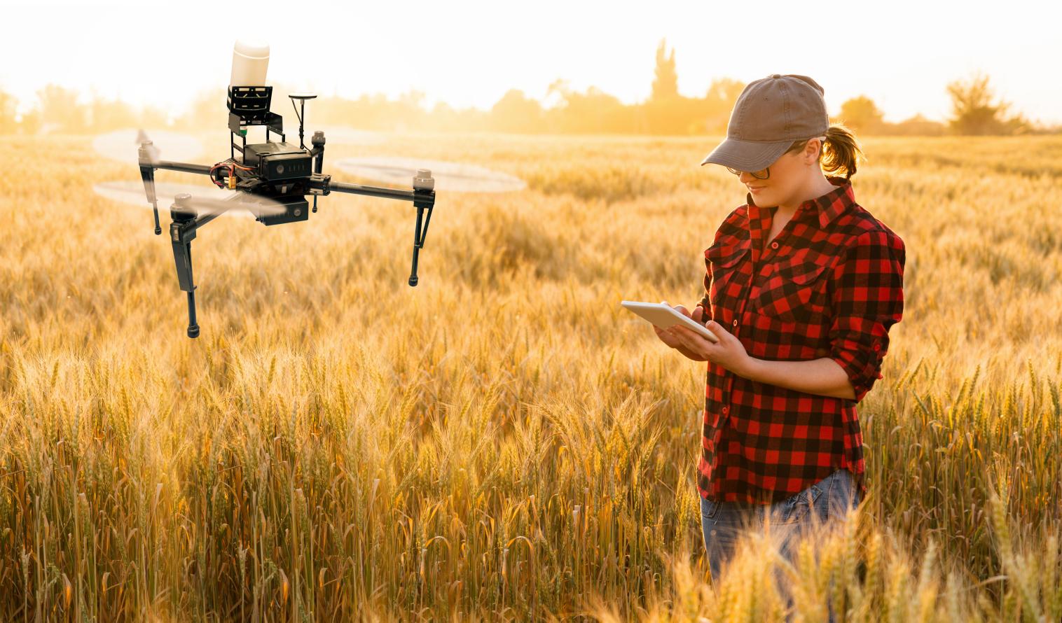 Landwirtin steht auf einem Feld mit einer Drohne