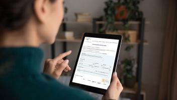 Eine Person betrachtet ein Tablet mit der Eingabemaske der Informationsplattform Klinische Studien in NRW