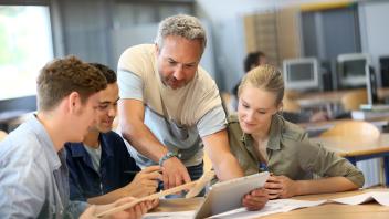 Lehrer arbeitet mit einer Gruppe von Studierenden auf einem Tablet 