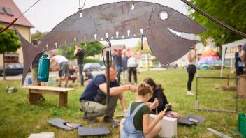 Menschen bei künstlerischen Handwerksarbeiten auf einer Sommerwiese