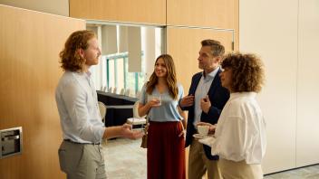 vier Personen führen vor einem Veranstaltungsraum ein Gespräch