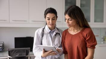 Ärztin zeigt einer Patientin den medizinischen Befund auf ihrem Tablet