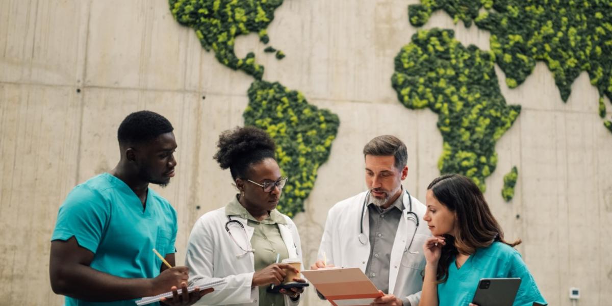 Ein internationales Ärzteteam aus zwei Frauen und zwei Männern bespricht gemeinsam Unterlagen. im Hintergrundsehen wir eine Weltkarte aus Pflanzen.
