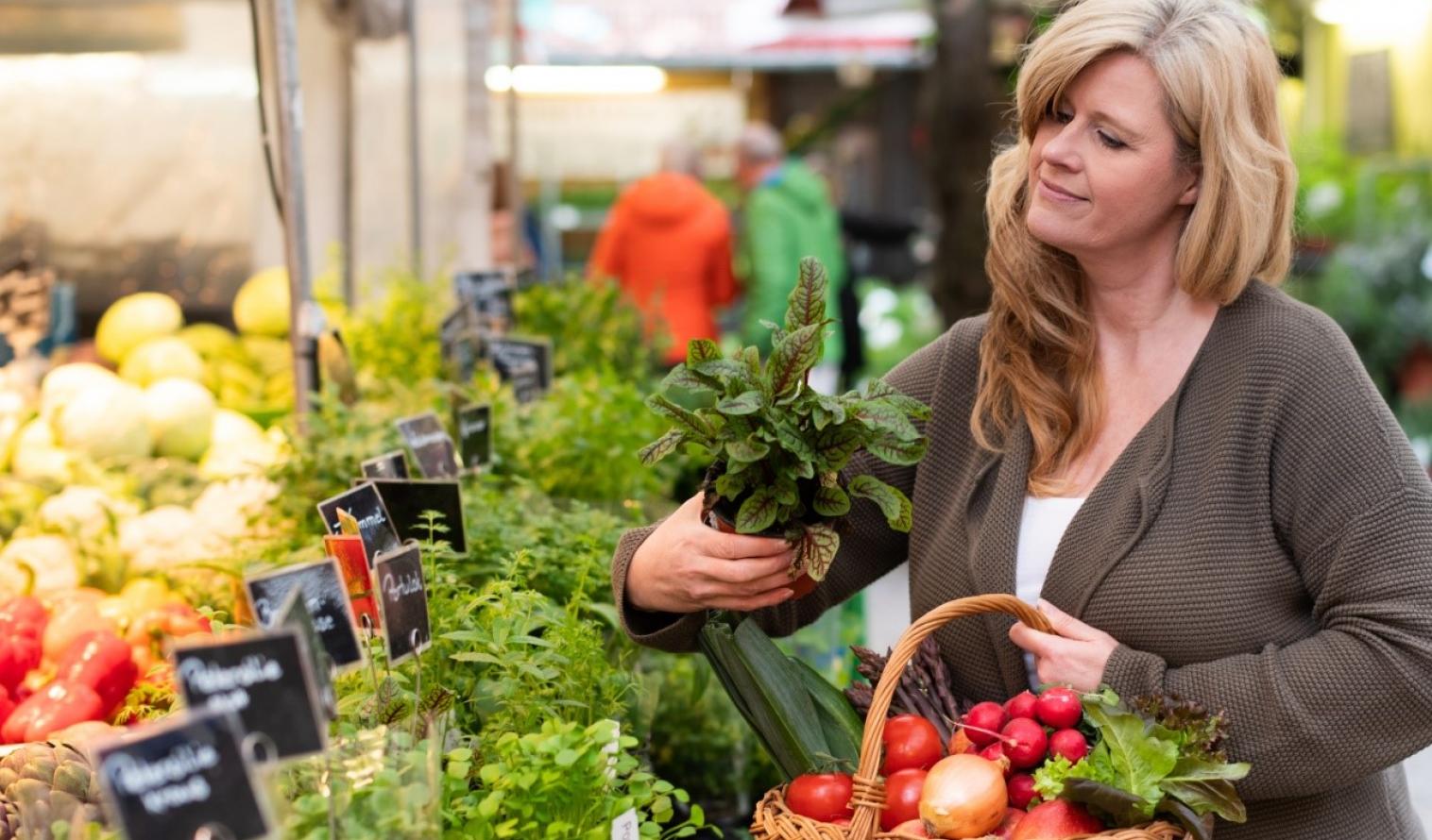 Frau prüft Gemüse auf dem Markt