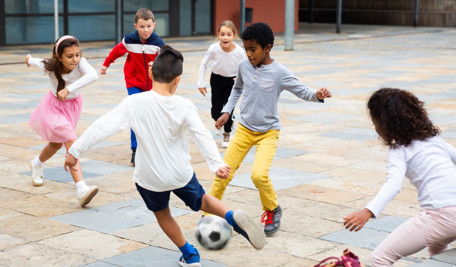 Schulkinder spielen mit einem Ball in der Nähe des Schulgebäudes