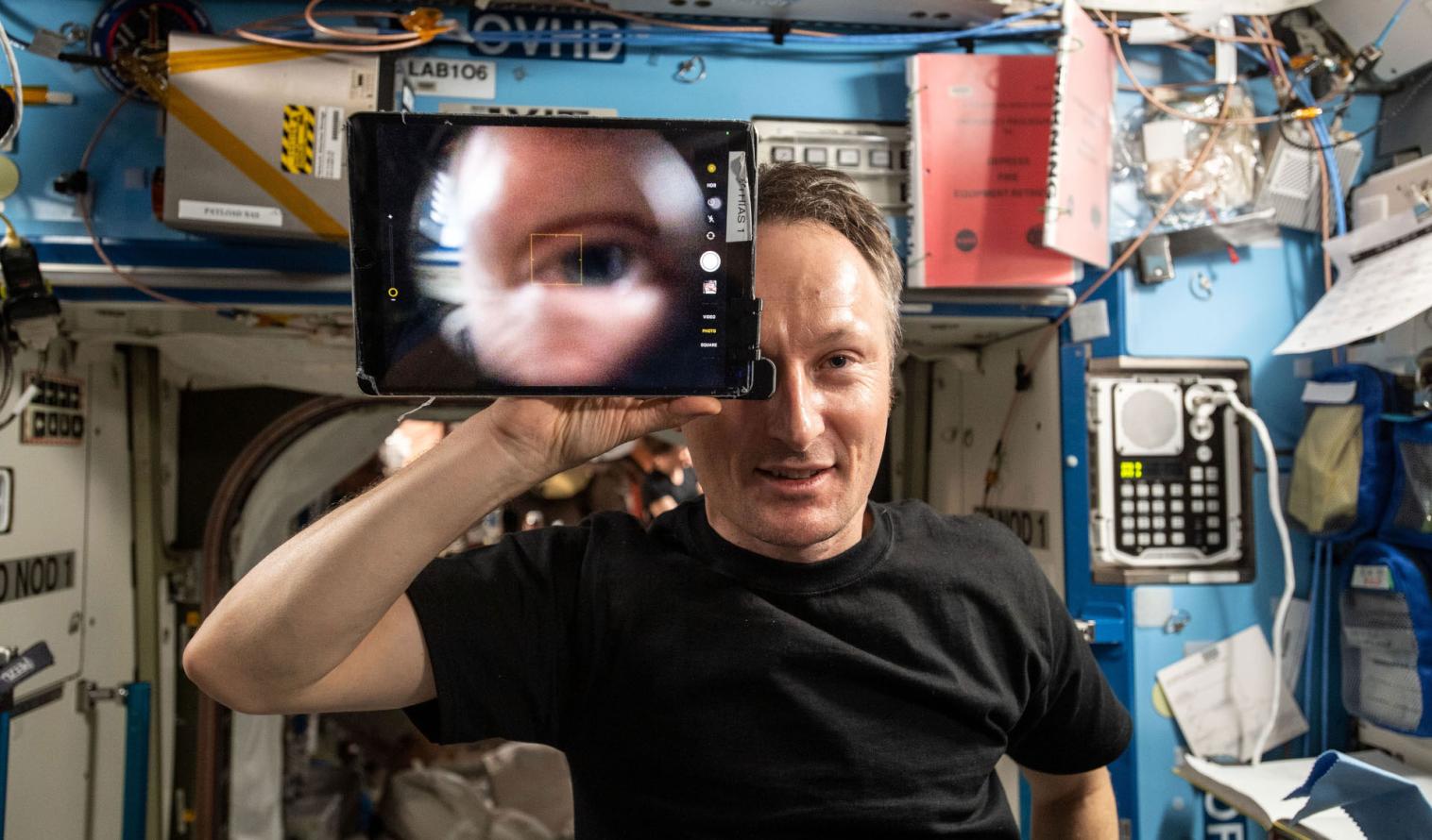Mann hält einen Retina-Scan in der Hand, um bei einer Weltraummission eine medizinische Diagnose ohne Arzt vor Ort erstellen zu können