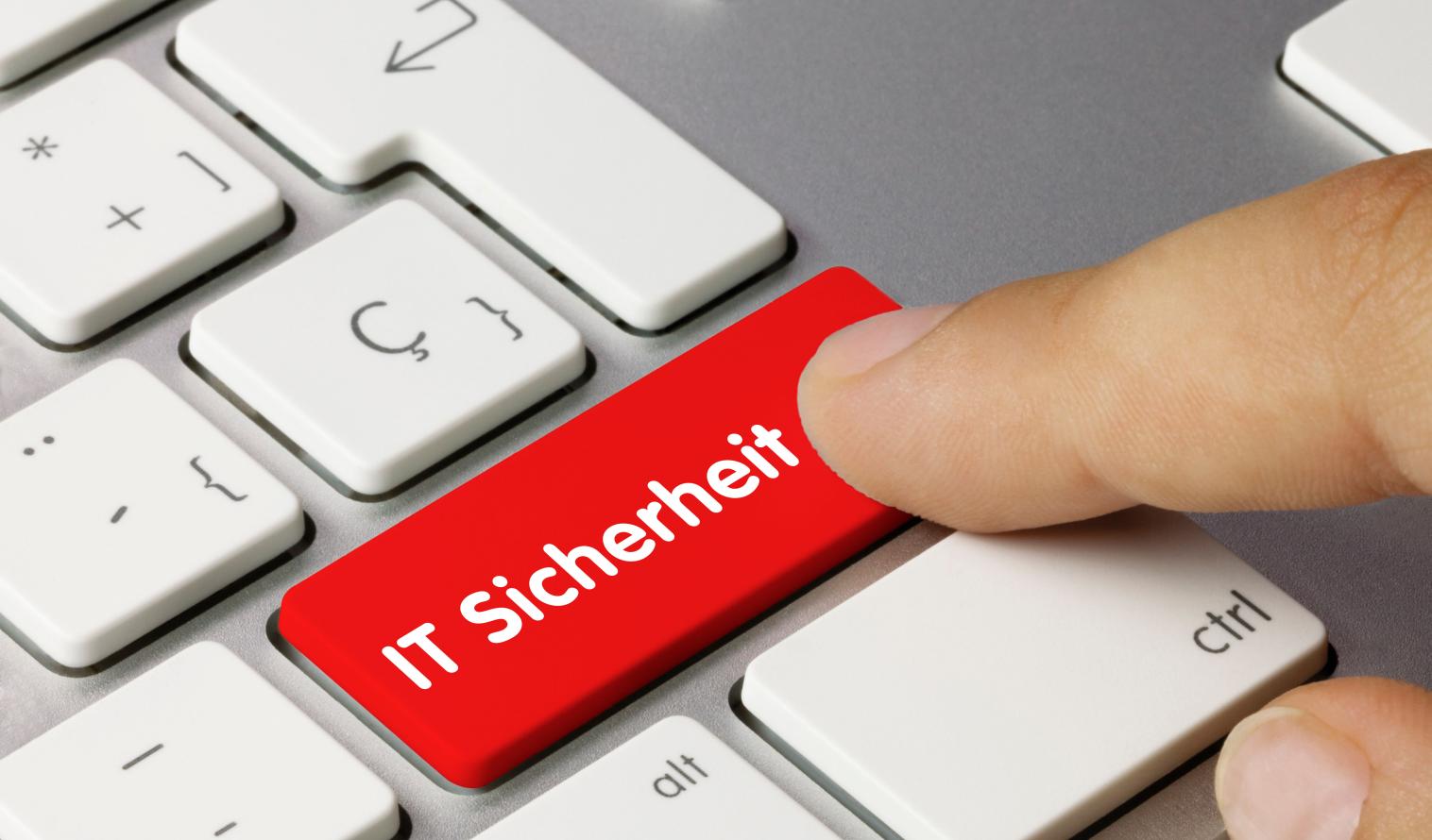 Ausschnitt einer Tastatur mit einer roten Taste IT-Sicherheit, eine Hand drückt auf diese Taste