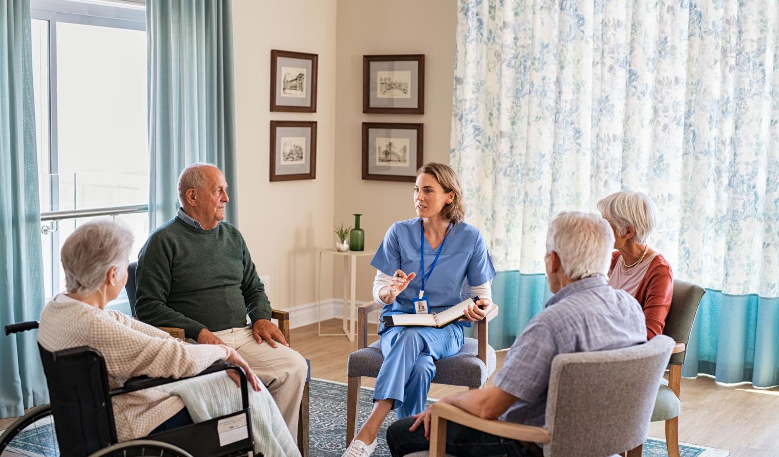 Krankenschwester im Gespräch mit älteren Menschen während einer Gruppentherapie
