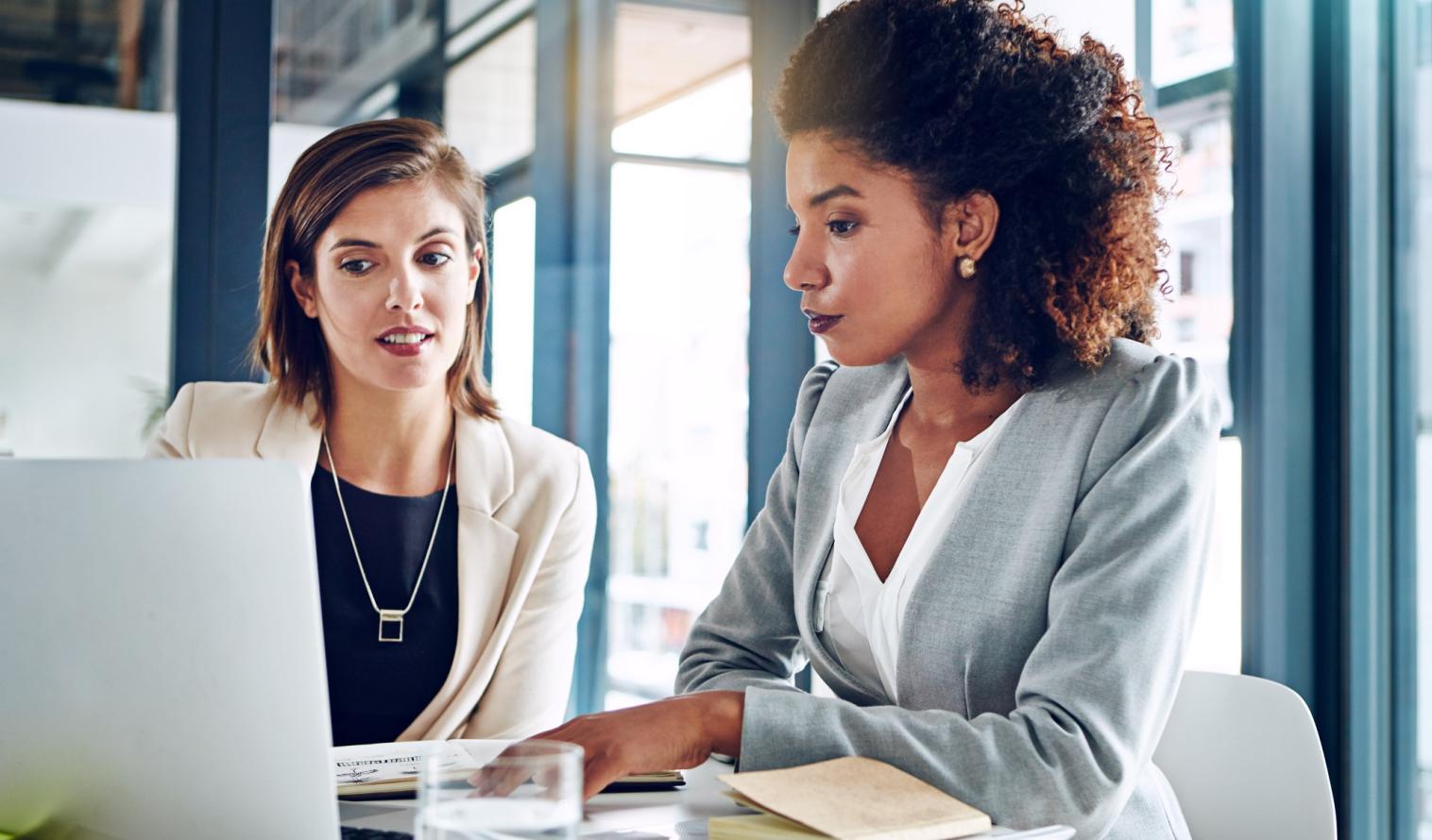 Zwei Frauen arbeiten gemeinsam in einem Büro und prüfen kritisch Unterlagen