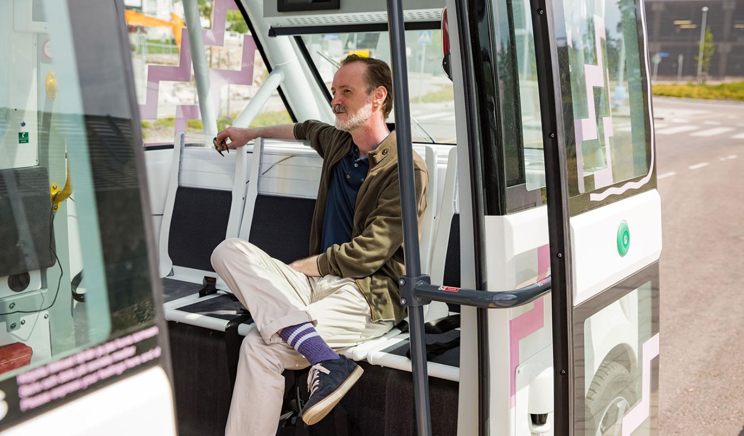 Mann sitzt in einem autonomen Bus