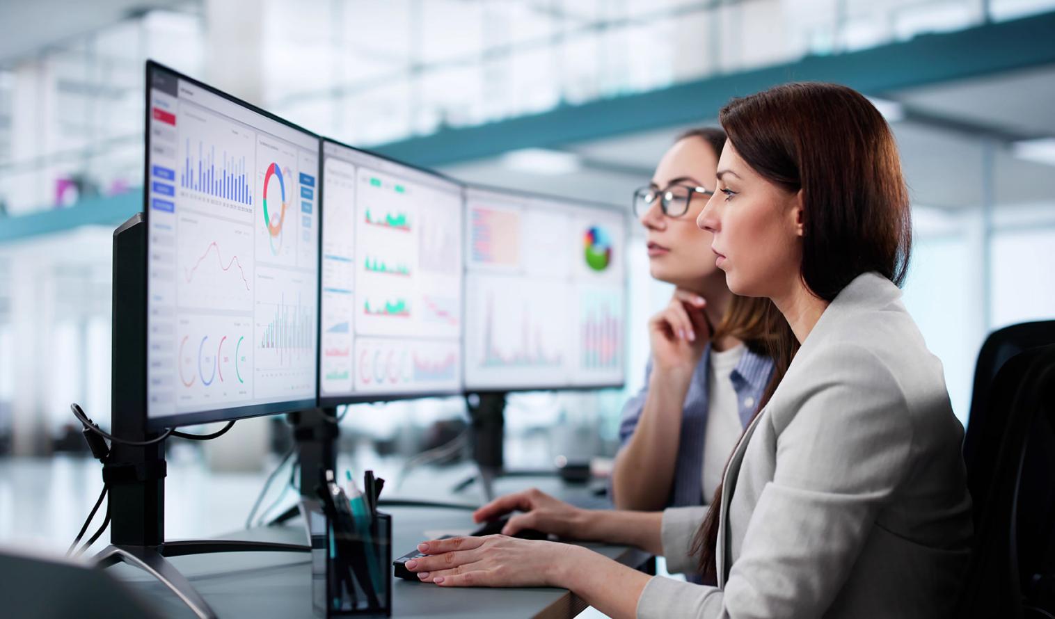 zwei Frauen sitzen an einem PC und werten Daten aus