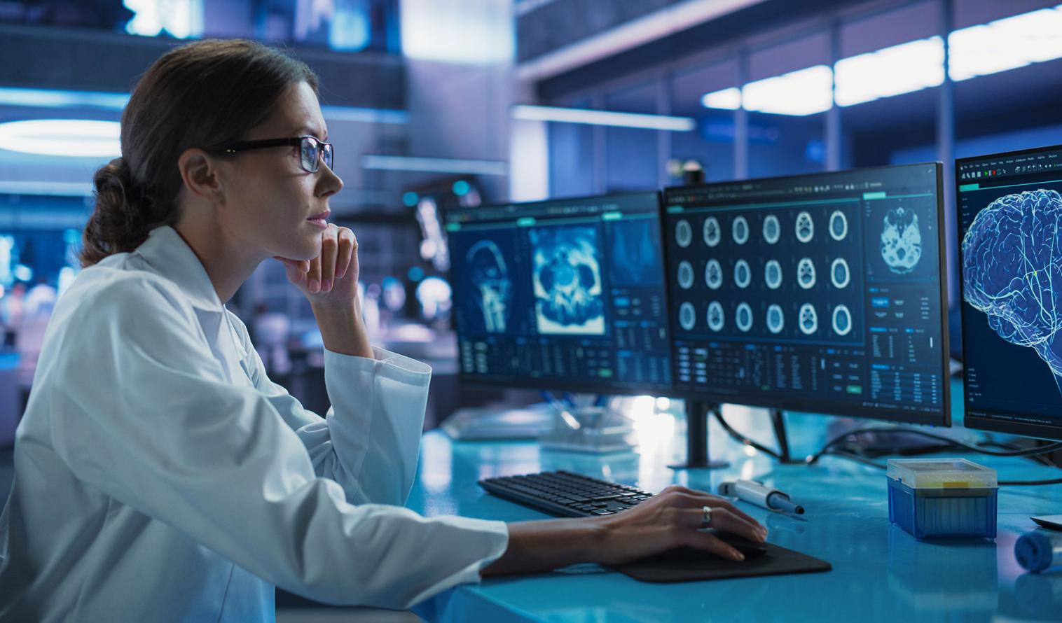 Medizinerin, die einen Computer mit MRT-Bildern von Gehirnscans benutzt.