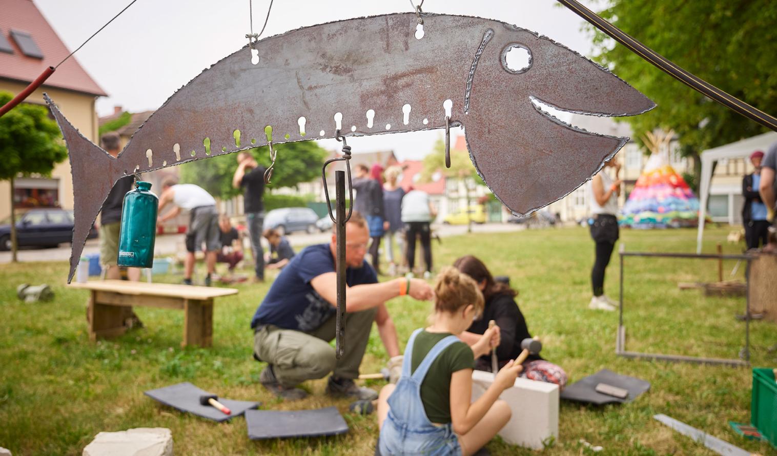 Menschen bei künstlerischen Handwerksarbeiten auf einer Sommerwiese