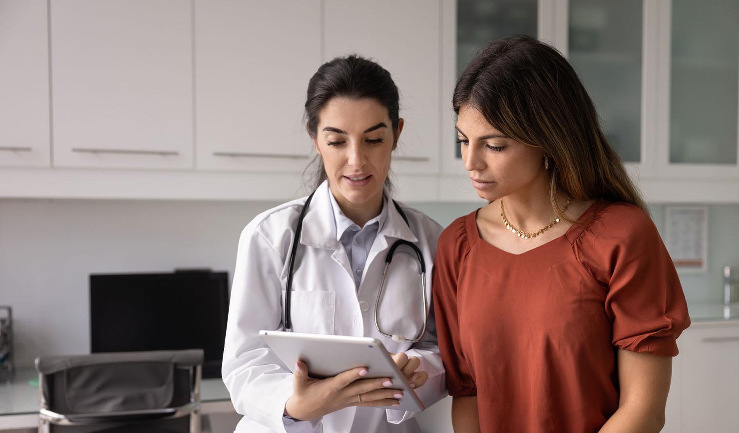 Ärztin zeigt einer Patientin den medizinischen Befund auf ihrem Tablet