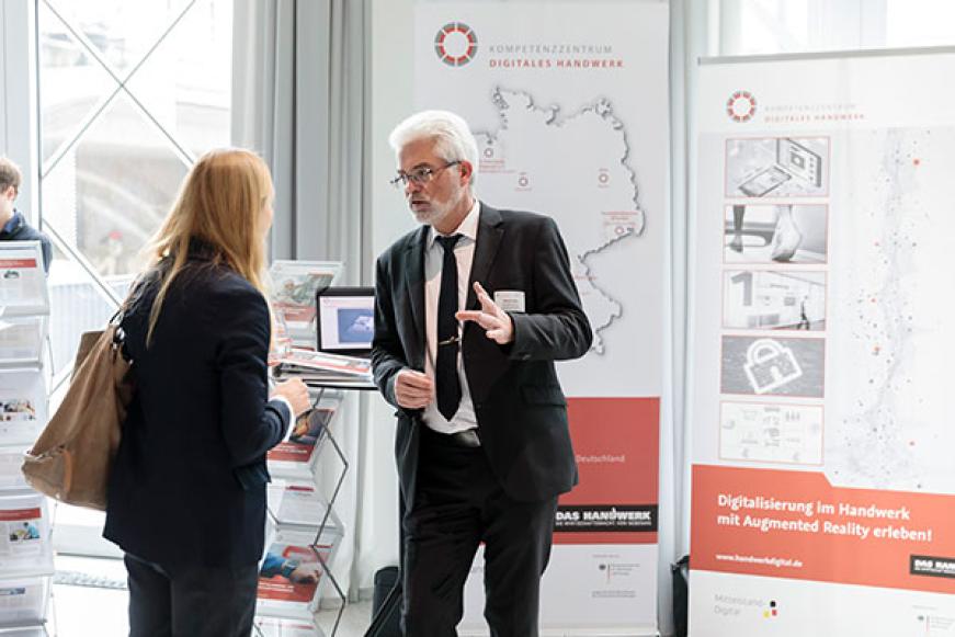 Eine Frau lässt sich an einem Messestand beraten.