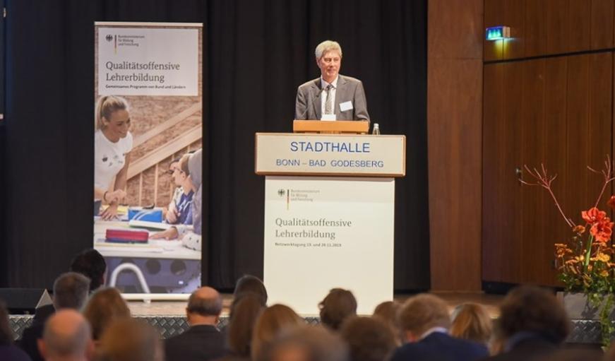 Dr. Stefan Luther vom BMBF steht auf der Bühne vor dem Publikum.