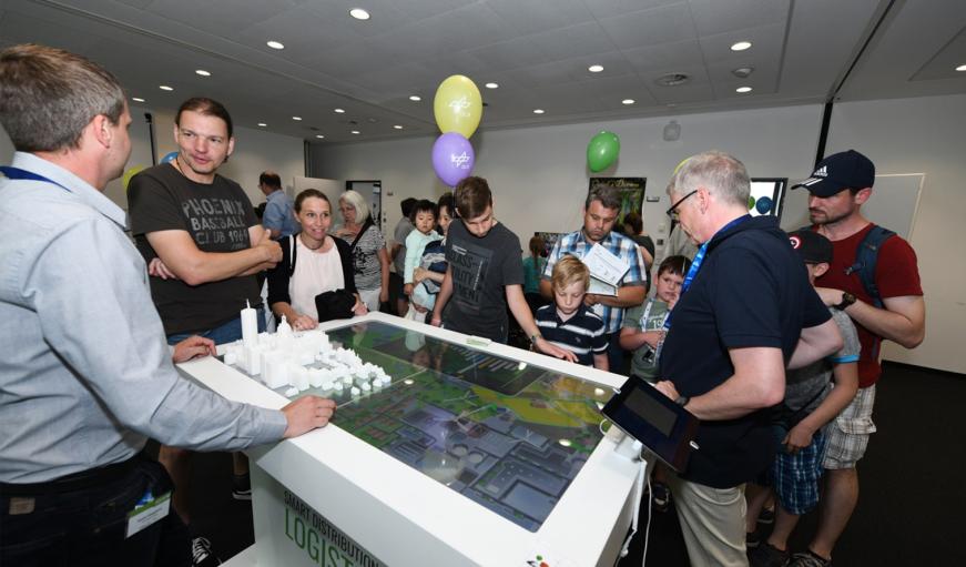 Eine Gruppe von Menschen steht um einen digitalen Tisch herum.