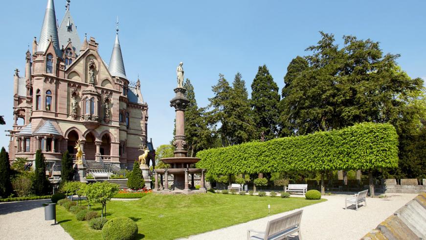 Schloss Drachenburg mit grüner Wiese und blauem Himmel.