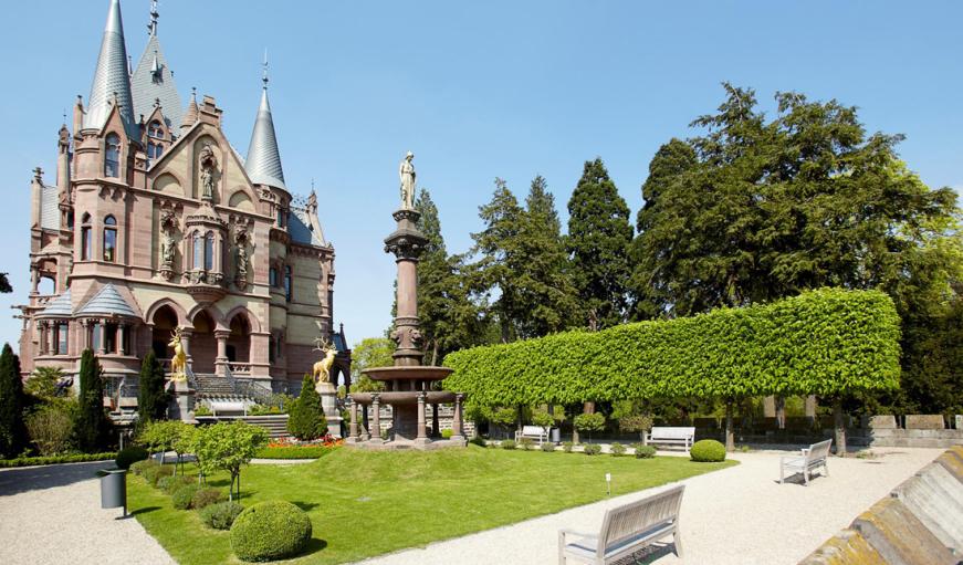 Schloss Drachenburg mit grüner Wiese und blauem Himmel.