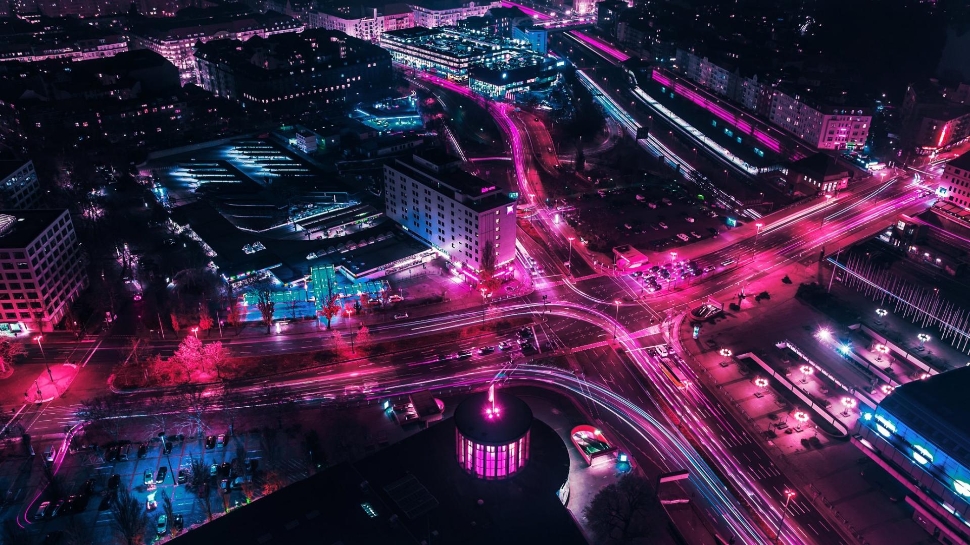 Stadt bei Nacht beleuchtet. Man sieht einen Verkehrsknotenpunkt von oben.