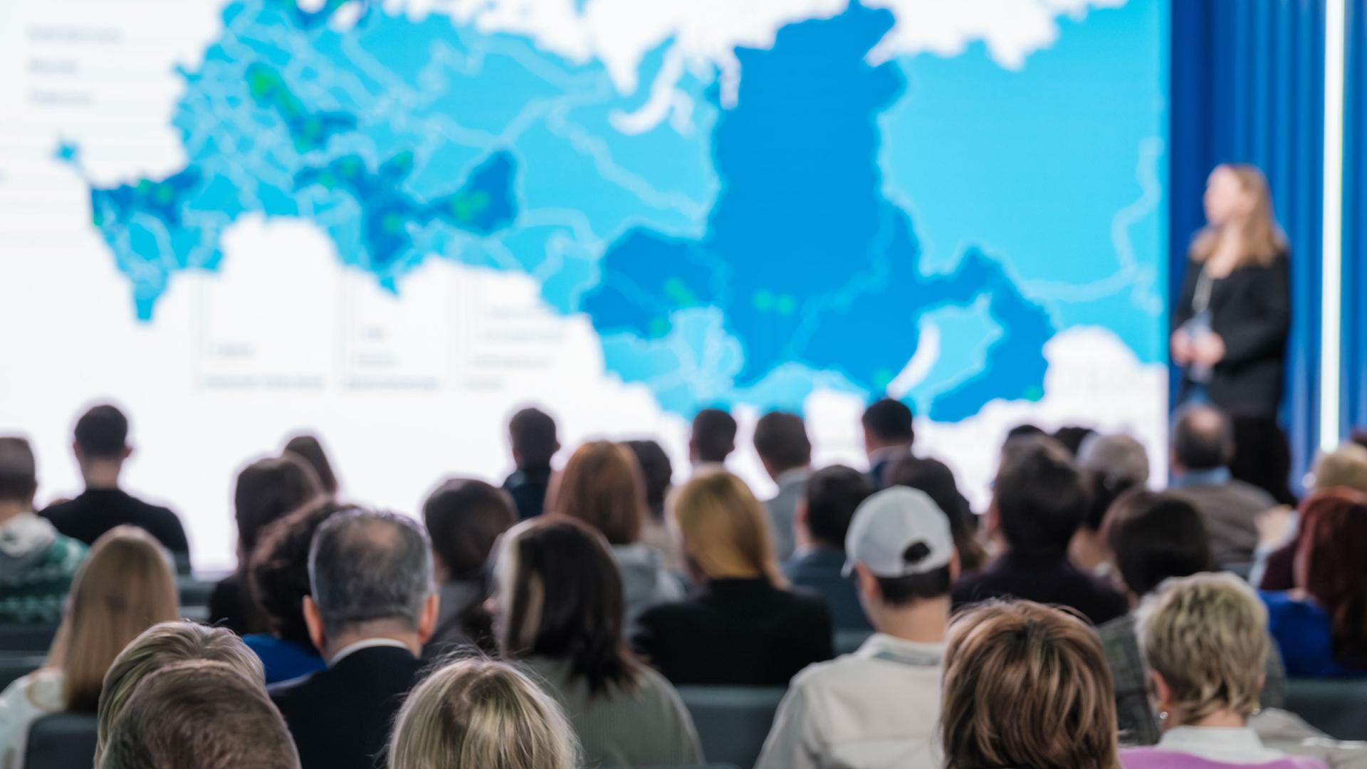 Sprecherin vor Publikum präsentiert eine Landkarte