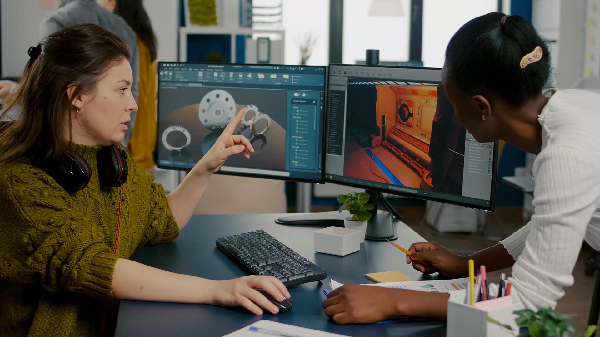 Zwei Mitarbeitende entwickeln das Design eines Spiels mithilfe eines PCs mit zwei Monitoren